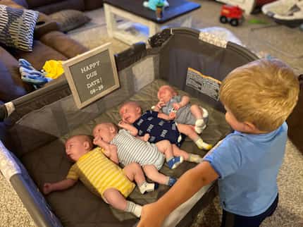 Katie and Chris Sturm's 3-year-old son, Ryan, looks over the quadruplets.