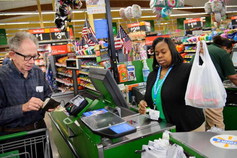 Wal-Mart employee Netanya Christian (right) bags up groceries for Marvin Stone (left) as he...