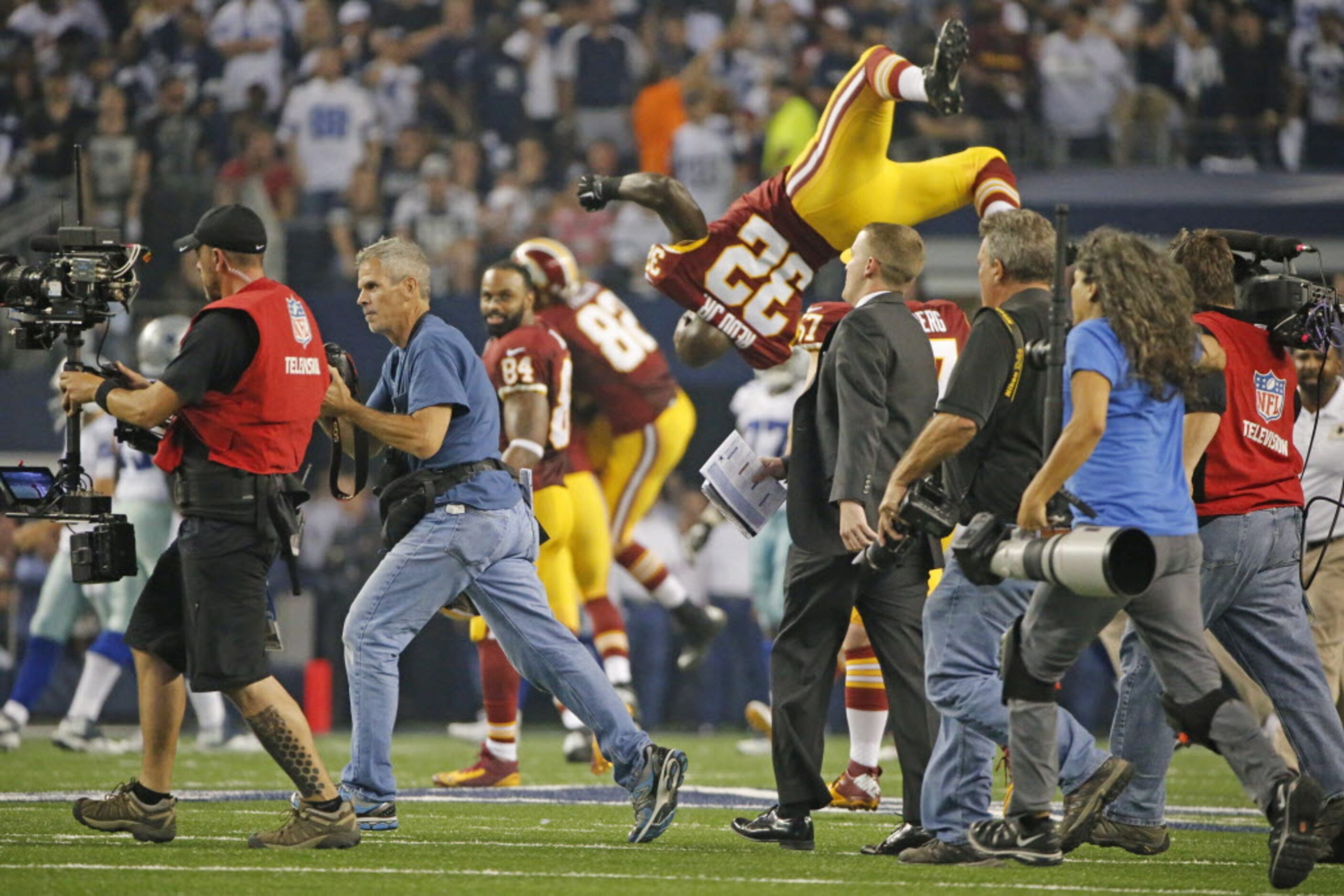 Washington Redskins running back Silas Redd (32) turns a backflip as he runs on the field...