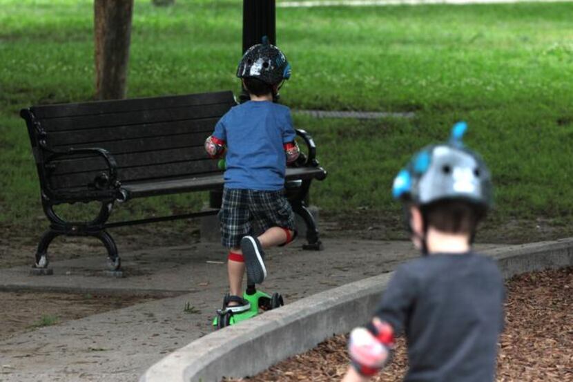 
Two brothers ride their scooters through Lindsley Park, which includes a playground and...
