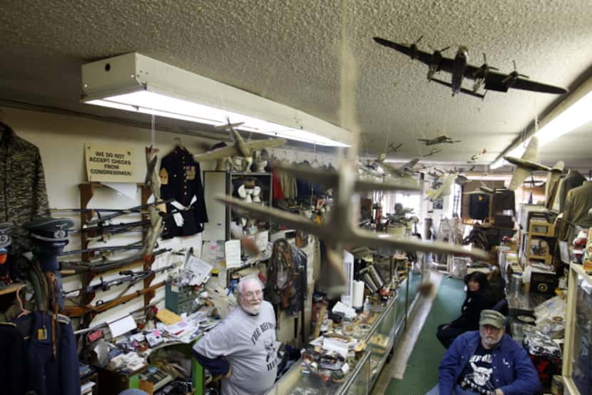 (left to right) The Recon Militaria store owner D.J. Goodwin sits behind the counter while...