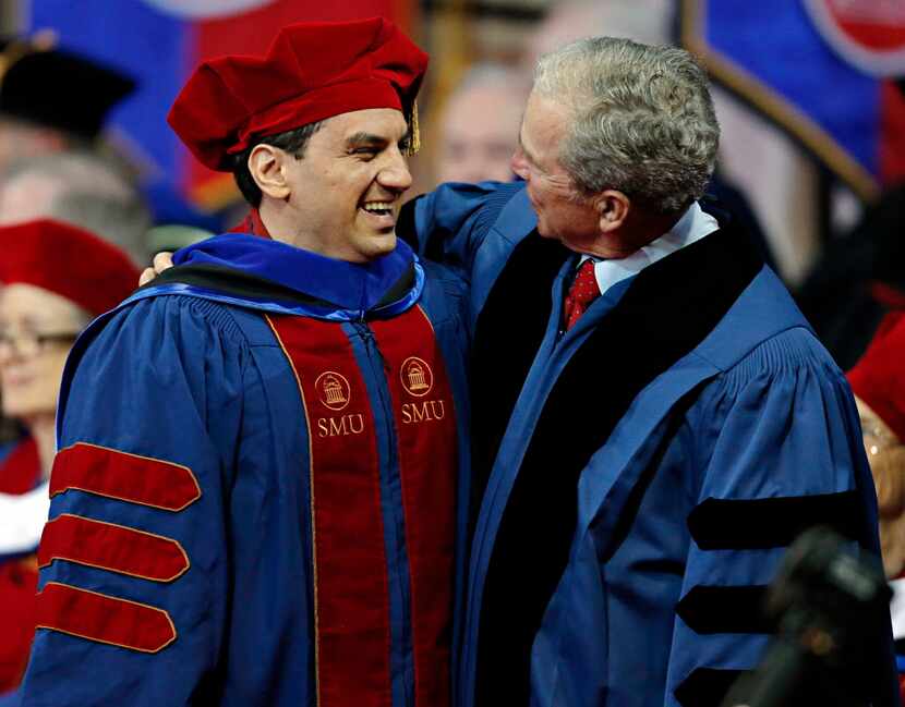 President George W. Bush (right) hugs a graduate during the SMU May Commencement Convocation...