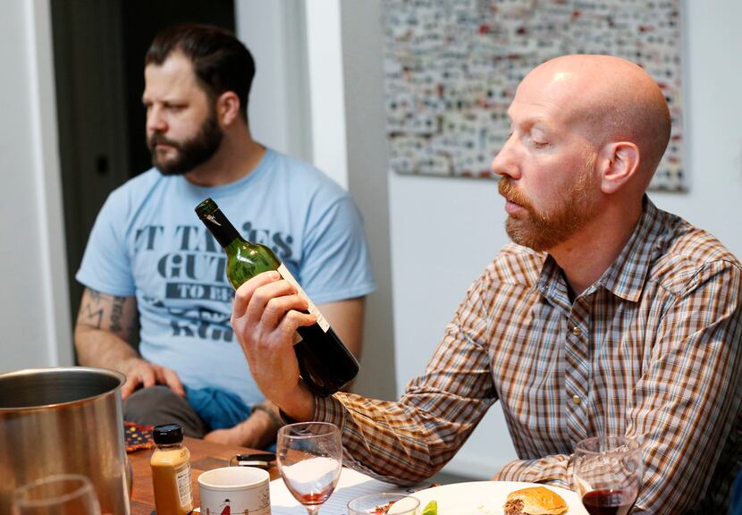 James Tidwell (right) reads the back of a wine bottle during a wine panel tasting with chef...