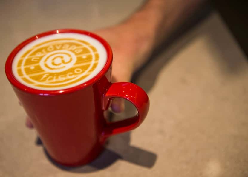Collin Mizell shows off a cup of coffee with a logo printed on the milk at Nerdvana Coffee...
