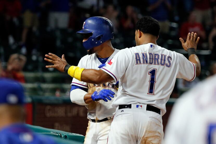 Texas Rangers' Carlos Gomez, rear, and Elvis Andrus (1) celebrate after Gomez scored on a...