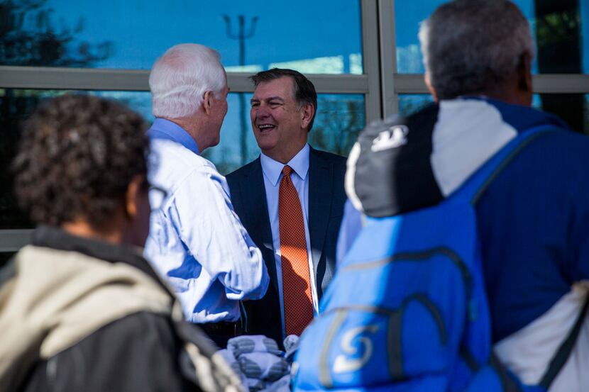 Dallas Mayor Mike Rawlings (center) talks with U.S. Sen. John Cornyn as they hand out socks,...