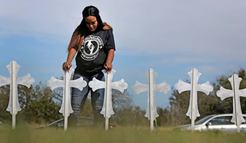 Sheree Rumph of San Antonio prays over 26 crosses placed near U.S. Highway 87 just down the...