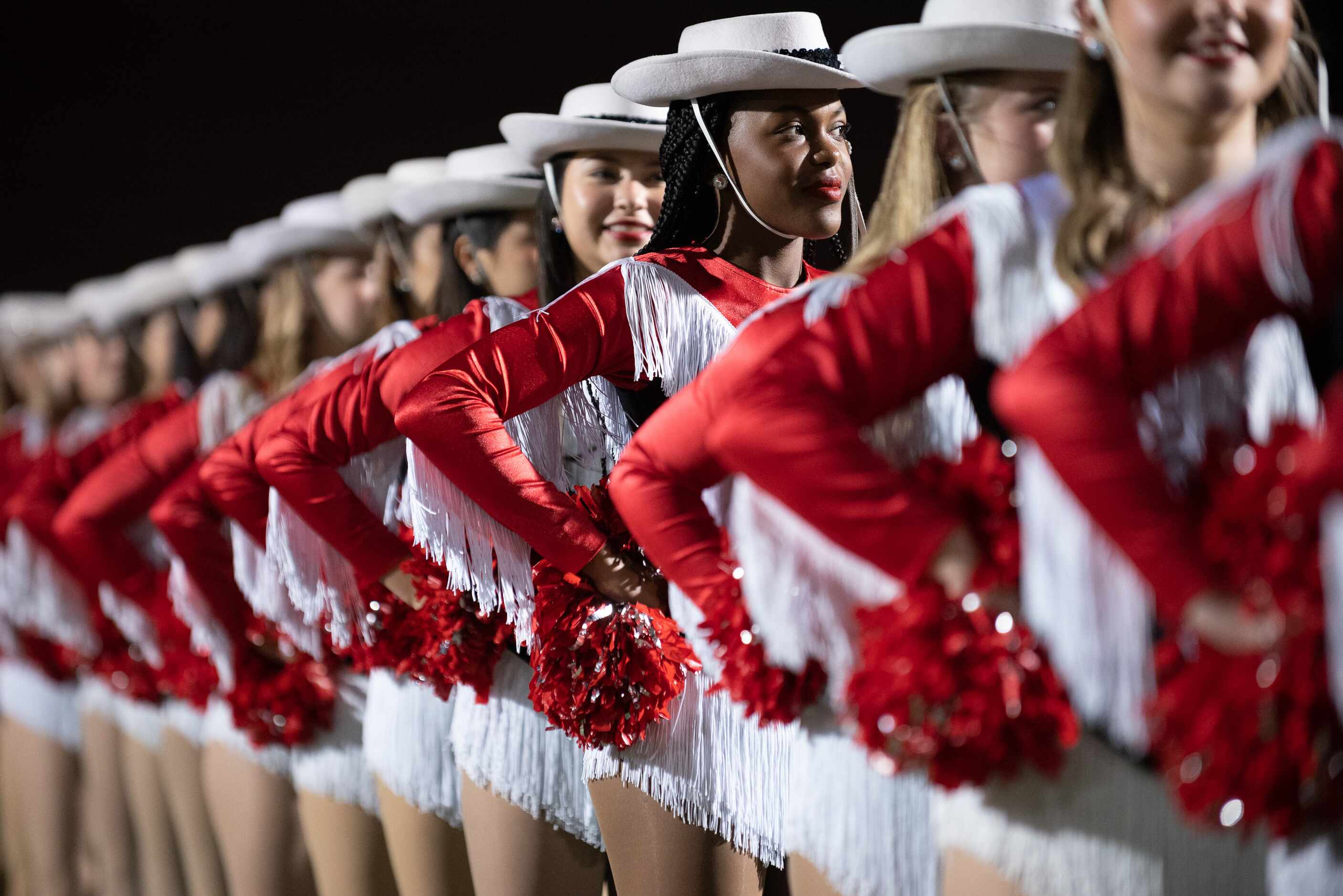 The dance team for the Coppell Cowboys stand as they wait for the start of a Thursday night...