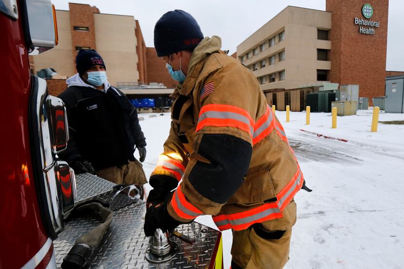 Arlington Fire Department Lt. Josh Jones hooks up a new water hose to Engine 4 in Arlington,...