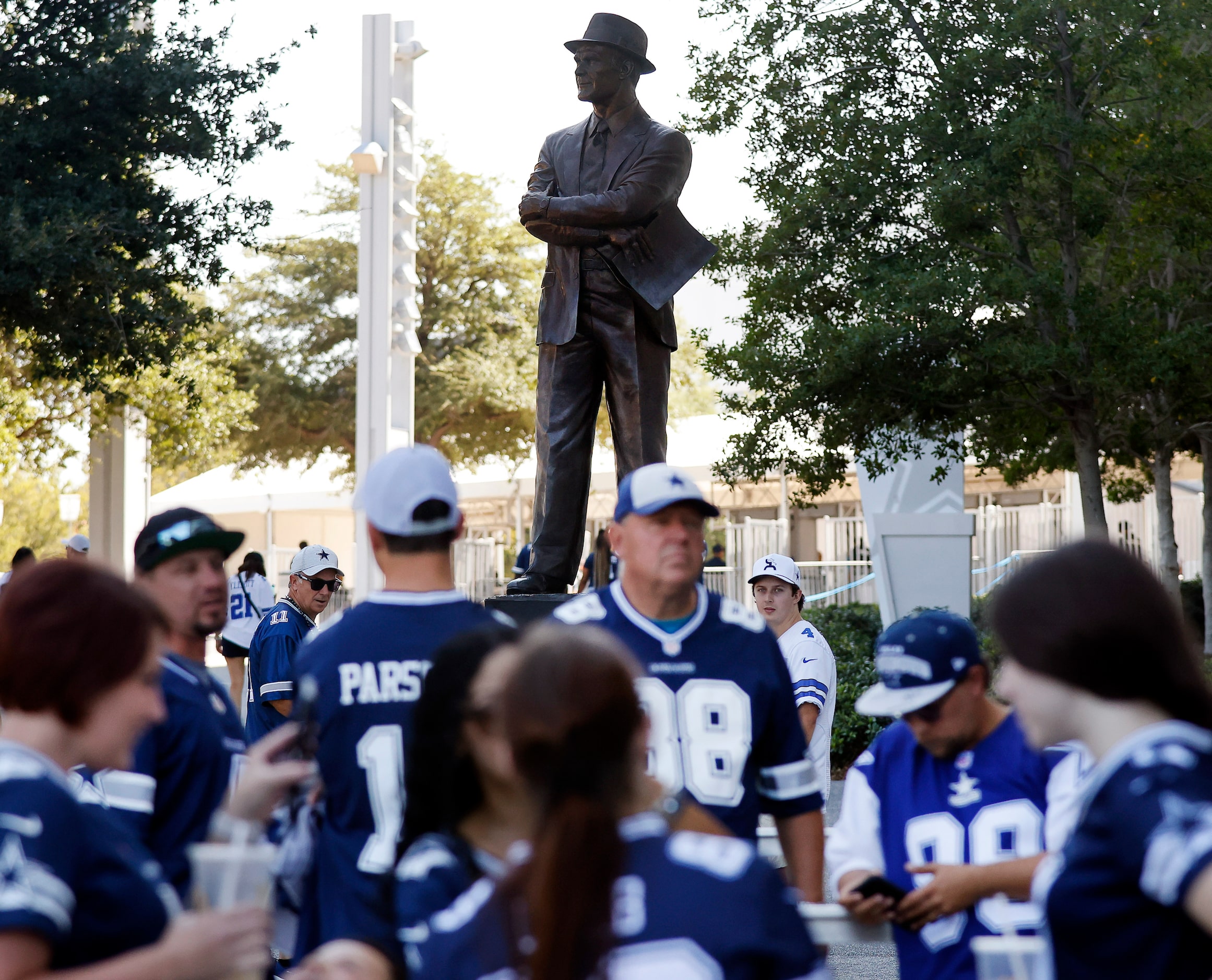 Before a statue of legendary head coach Tom Landry, Dallas Cowboys fans wait to enter the...