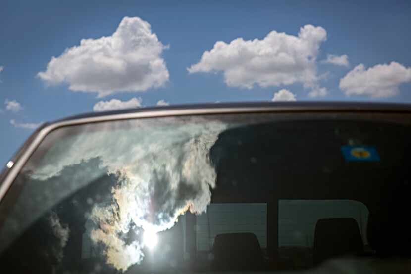 Hot sun is reflected in the windshield of a car parked in downtown Dallas.