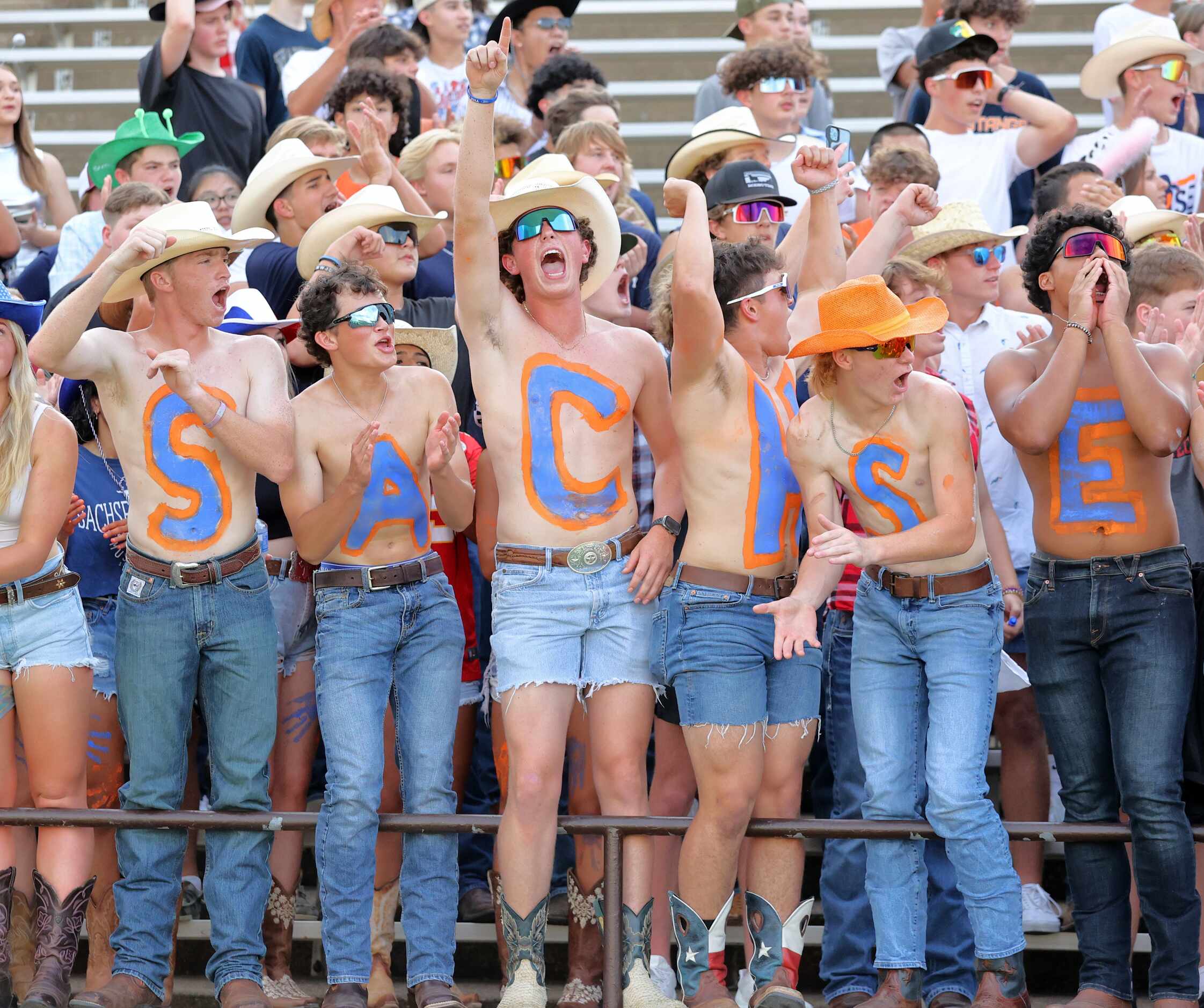 Sachse student boosters, with SACHSE painted on their chests, cheer during the first half of...