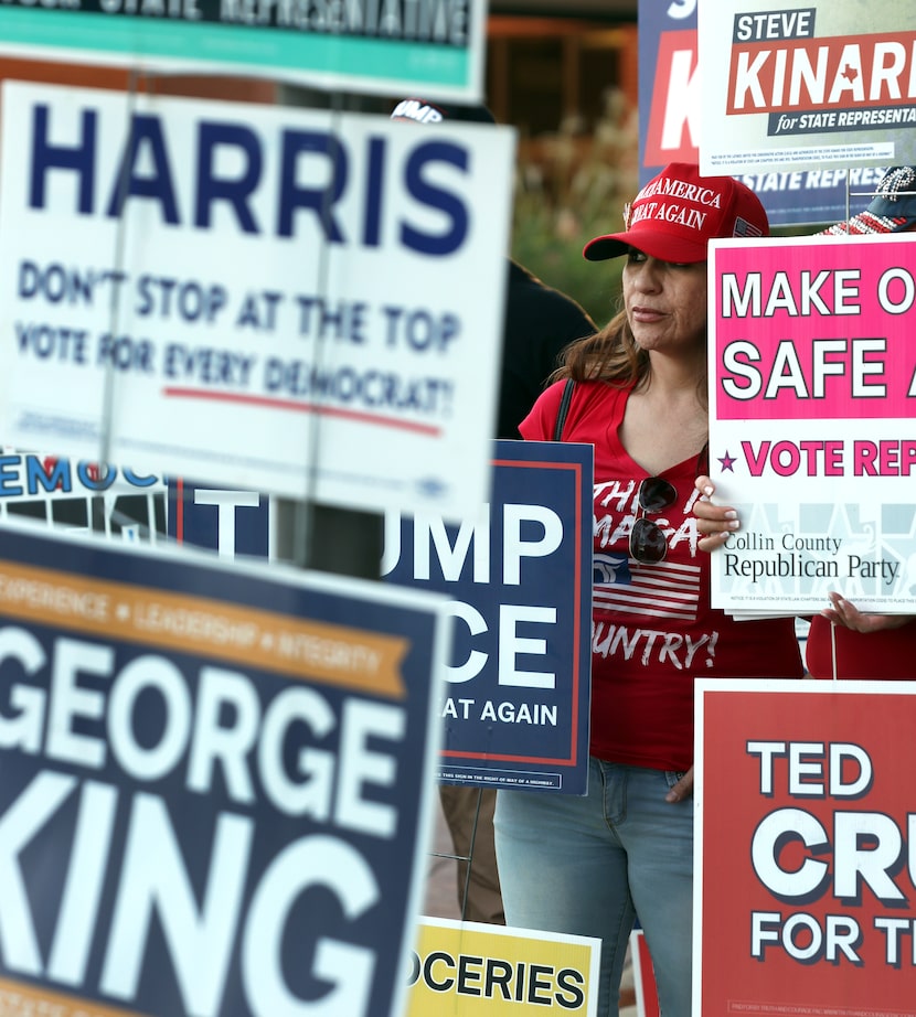 Framed by a sea of campaign posters, Nadia Salvino waits to greet voters as they approach...