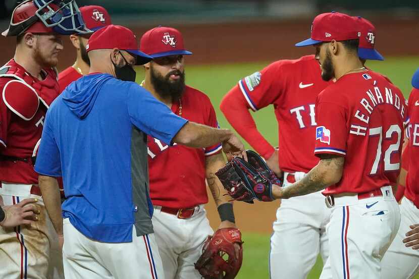 Texas Rangers manager Chris Woodward hands the ball over to pitcher Jonathan Hernandez after...