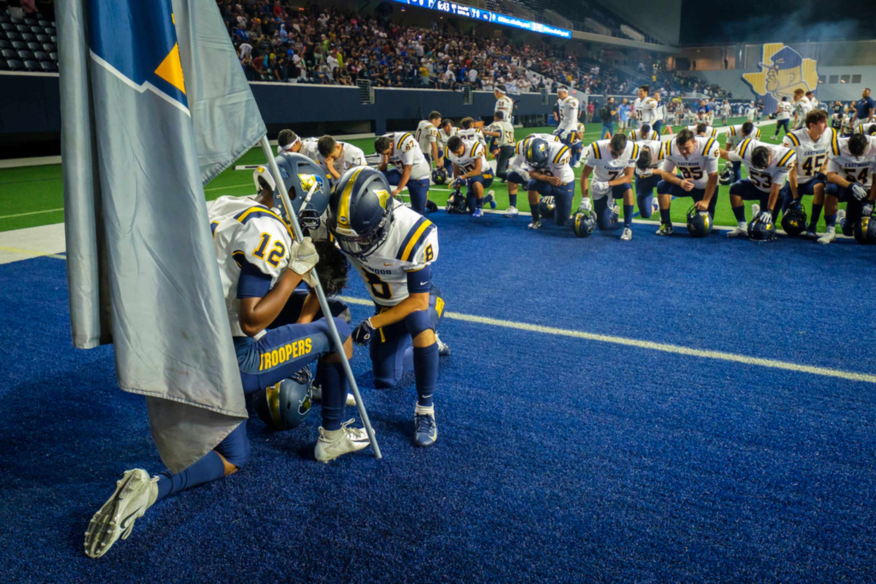 El Paso Eastwood players kneel in prayer before a high school football game against the...