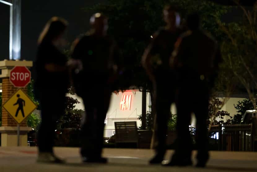 Store front logo of H&M at Allen Premium Outlets is seen through law enforcement officers as...