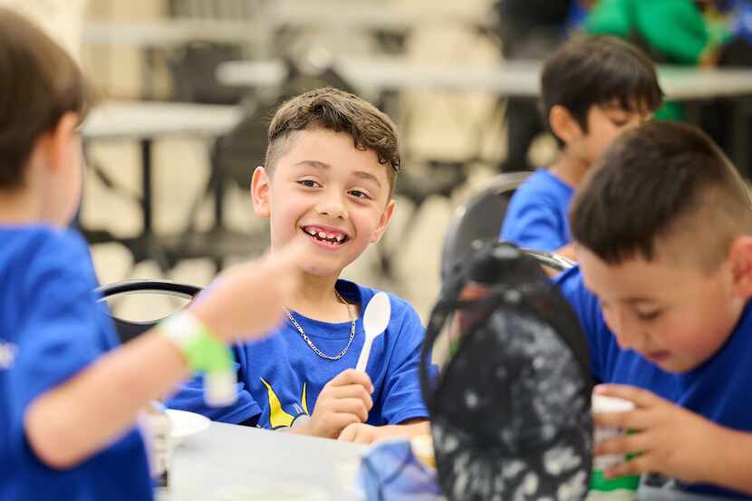 Smiling children participate in summer meal program, wearing blue shirts.