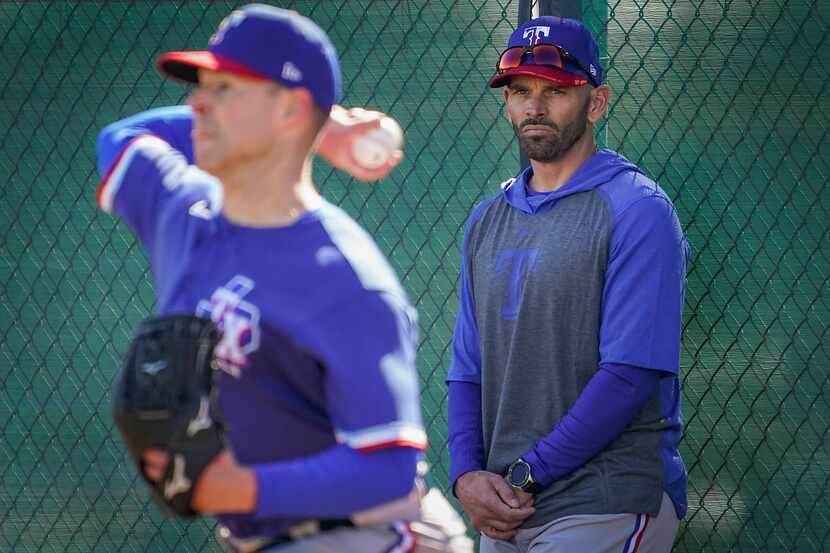 Texas Rangers pitcher Corey Kluber throws in the bullpen as manager Chris Woodward looks on...