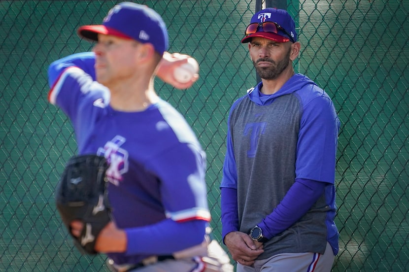 Texas Rangers pitcher Corey Kluber throws in the bullpen as manager Chris Woodward looks on...