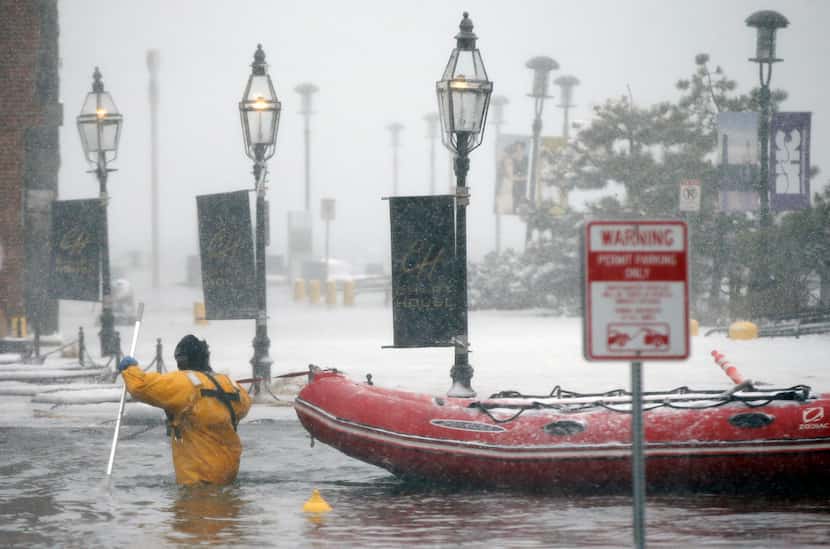 BOSTON, MA: A Boston firefighter wades through flood waters from Boston Harbor on Long Wharf...