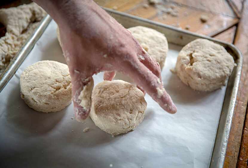 Chef Tim Byres lays buttermilk biscuits in rows on parchment paper. 