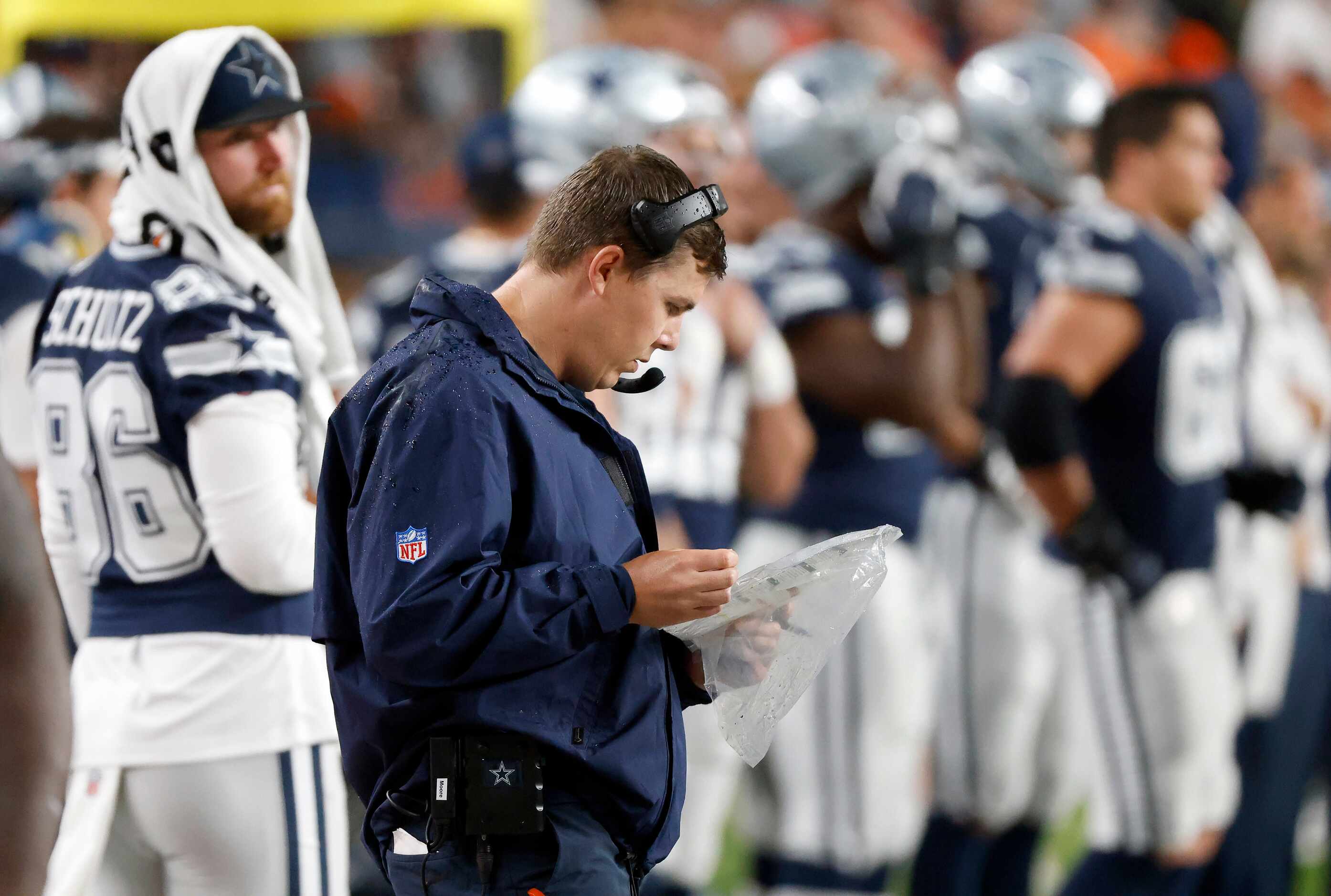 Dallas Cowboys offensive coordinator Kellen Moore looks over his play sheet as he paces the...