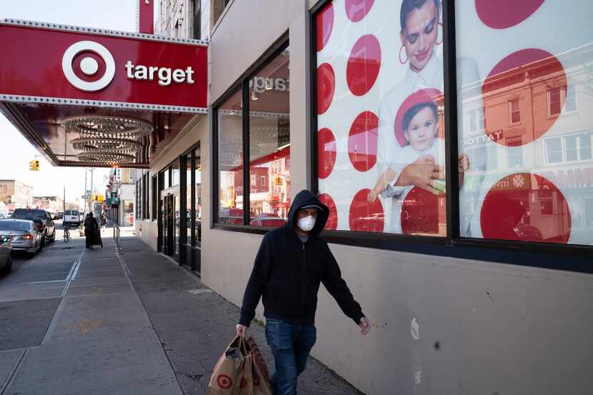 A customer wearing a mask carries his purchases as he leaves a Target store during the...