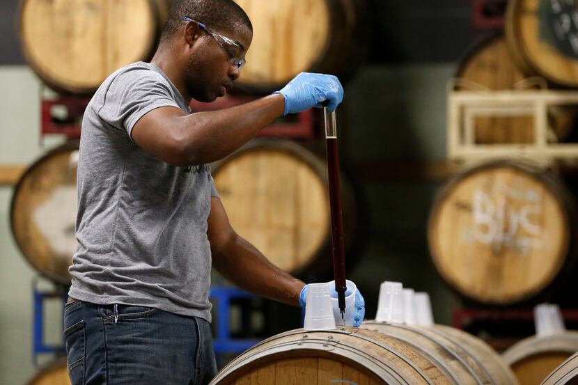Barrett Tillman, brewer at Deep Ellum Brewing Co., works on pulling samples from barrels...