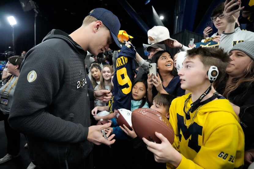 Michigan quarterback J.J. McCarthy signs autographs during media day ahead of the national...