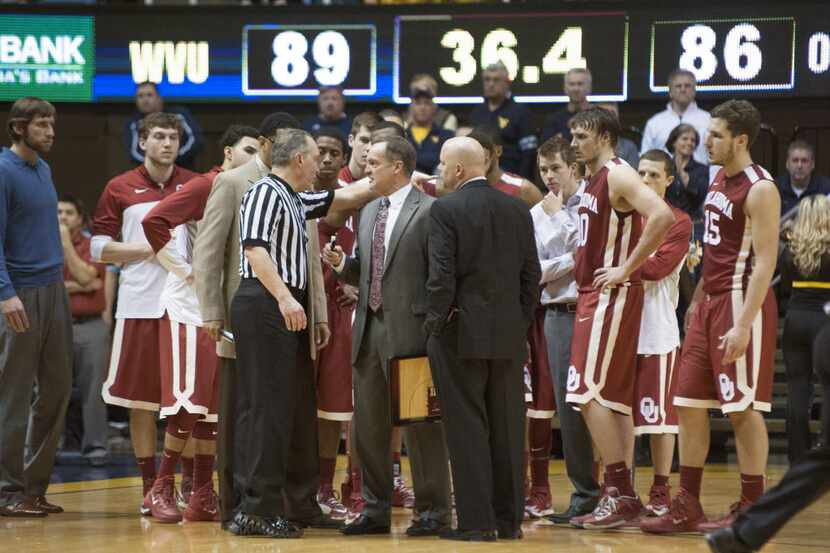 Oklahoma's Lon Kruger, middle,  speaks to an official during a timeout in overtime of an...
