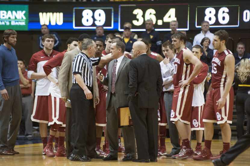 Oklahoma's Lon Kruger, middle,  speaks to an official during a timeout in overtime of an...
