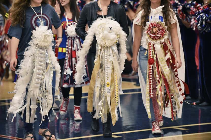 Students with giant mums walk through the gym at the 2015 Ryan High School homecoming pep...