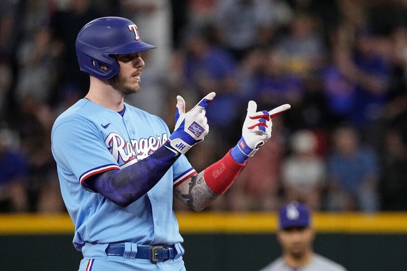 Texas Rangers' Jonah Heim gestures to his dugout after hitting a two-RBI double against the...