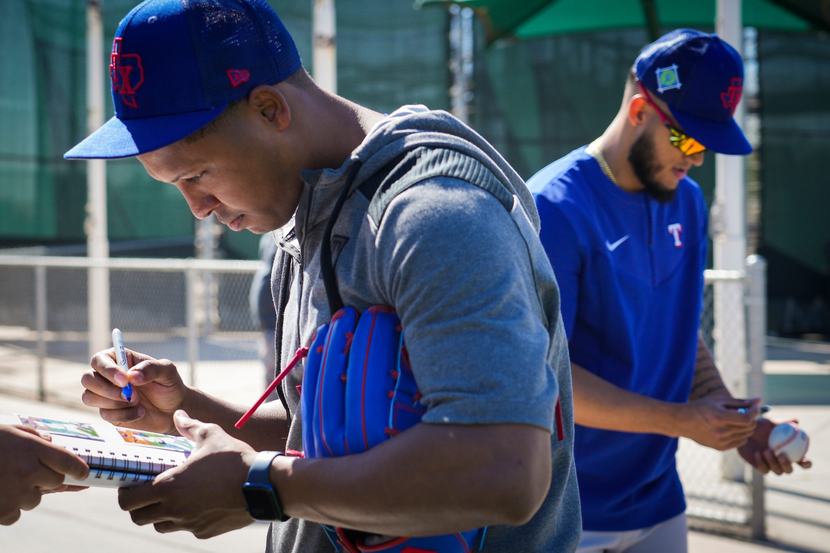 Texas Rangers pitchers José Leclerc (right) and Jonathan Hernández sign autographs for fans...