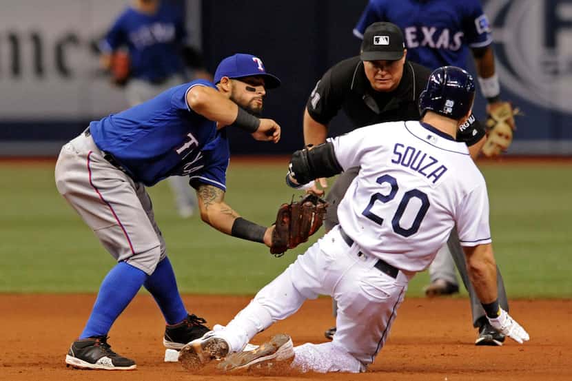 Umpire Marvin Hudson, center, watches as Texas Rangers' Rougned Odor, left, tags out  Tampa...