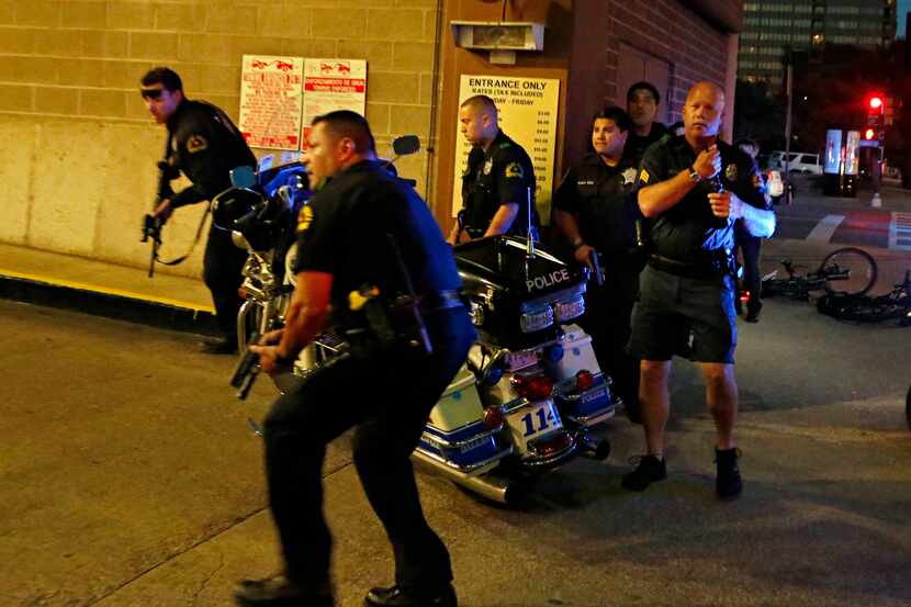 Police officers run with guns drawn into a parking garage during the deadly shooting. (G.J....