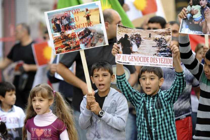 
Children hold placards reading “Stop the genocide of Yazidis“ as they take part in a...