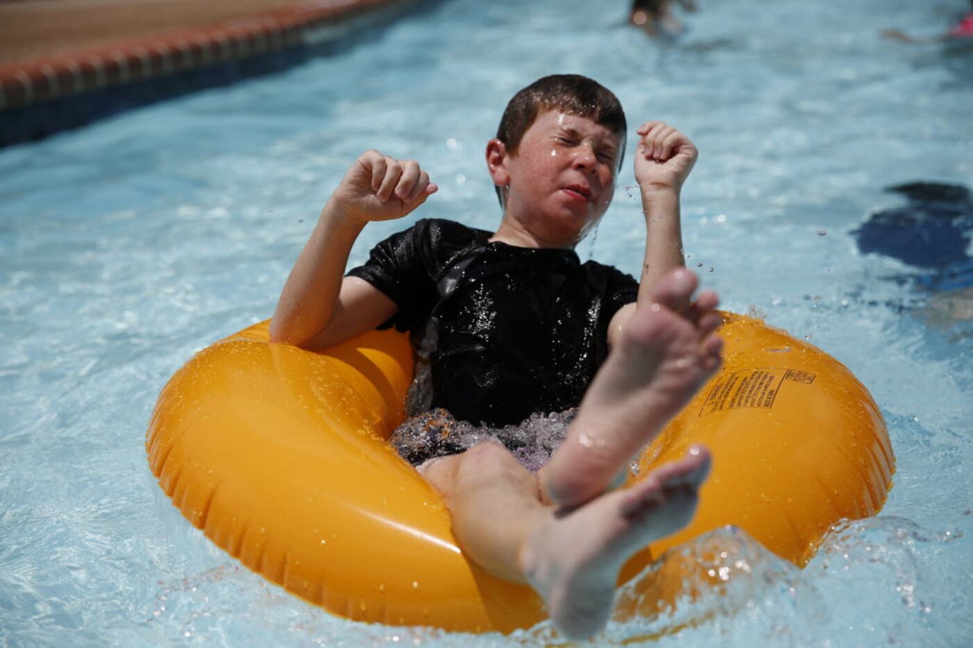 Matthew Olson, 11, of Plano, settles on a tube while swimming during an Independence Day...