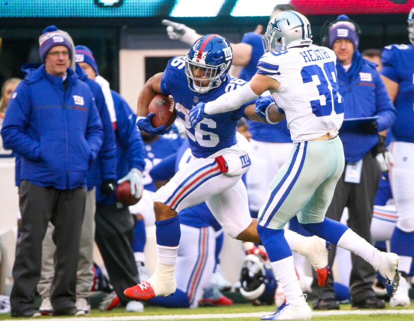 New York Giants running back Saquon Barkley (26) stiff arms Dallas Cowboys strong safety...