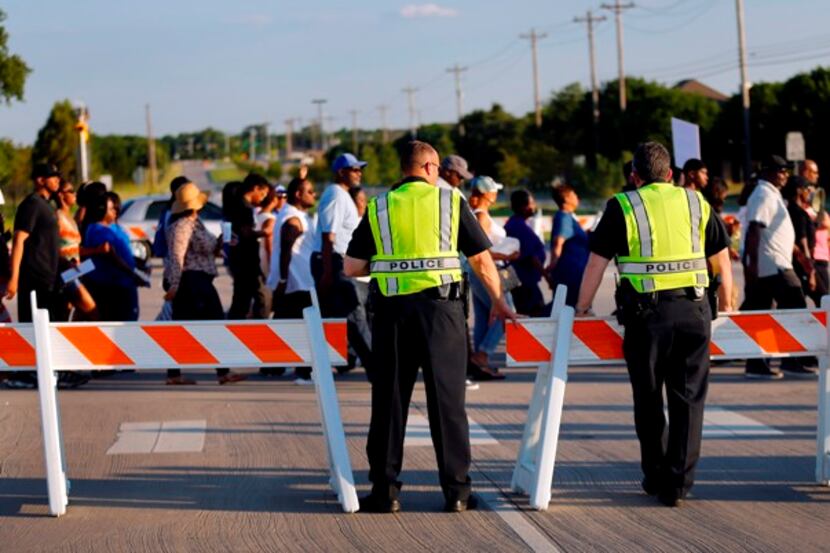 McKinney police watch as protesters march through the intersection of Alma Rd. and Silverado...