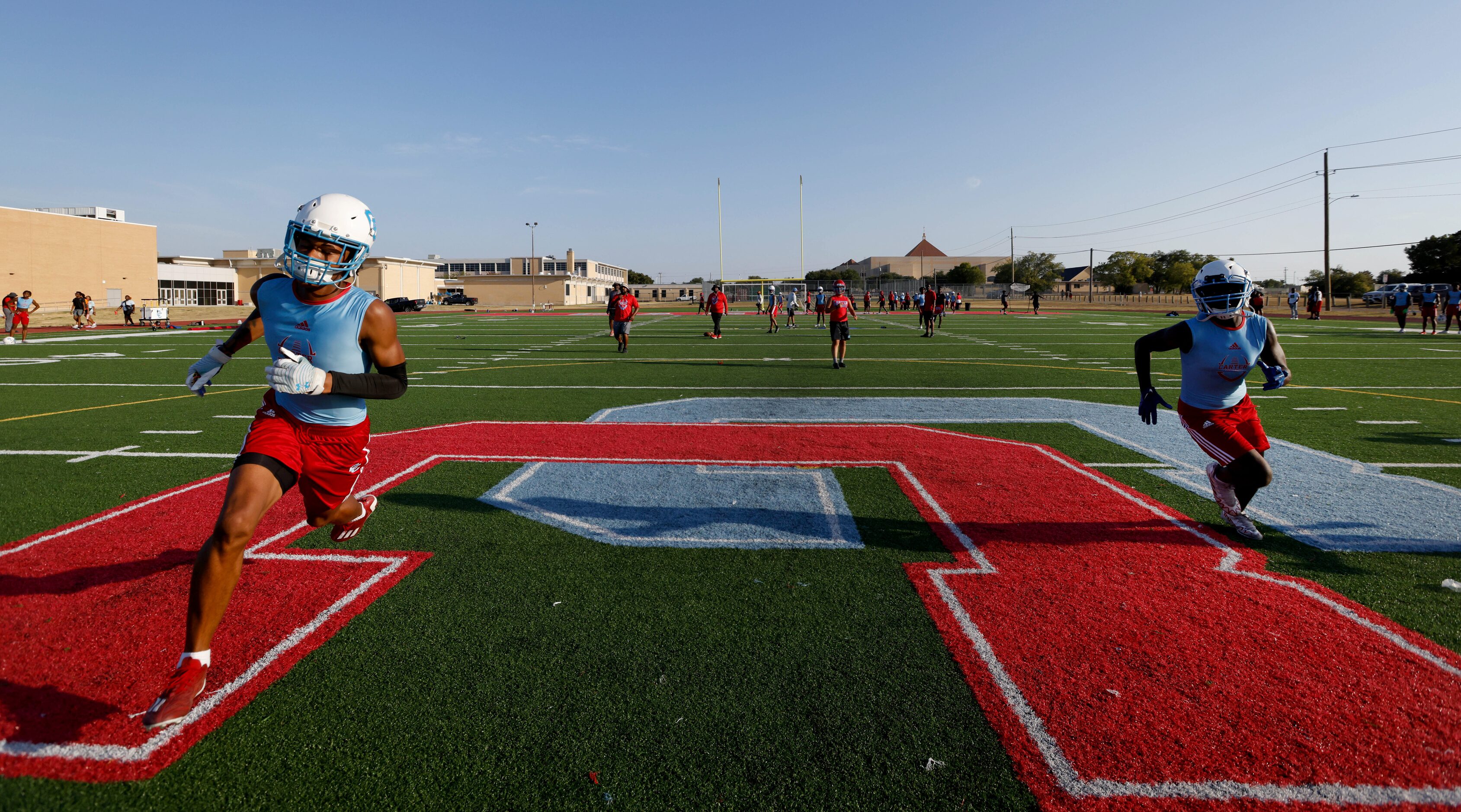 Charles Williams (left) and Jaleen Jones (right) run across the Carter Cowboys logo as part...