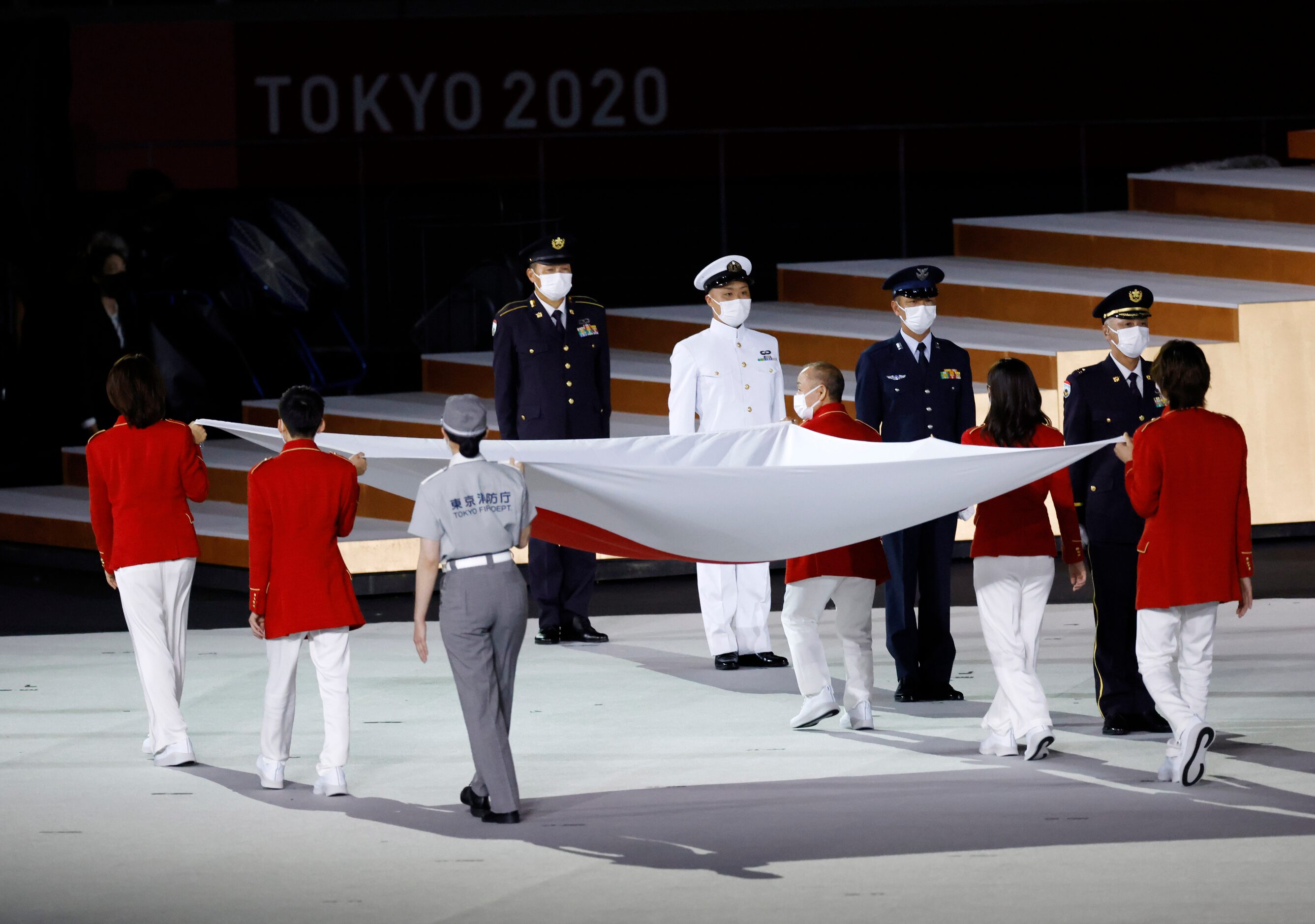 The flag of Japan is carried to be raised during the opening ceremony for the postponed 2020...