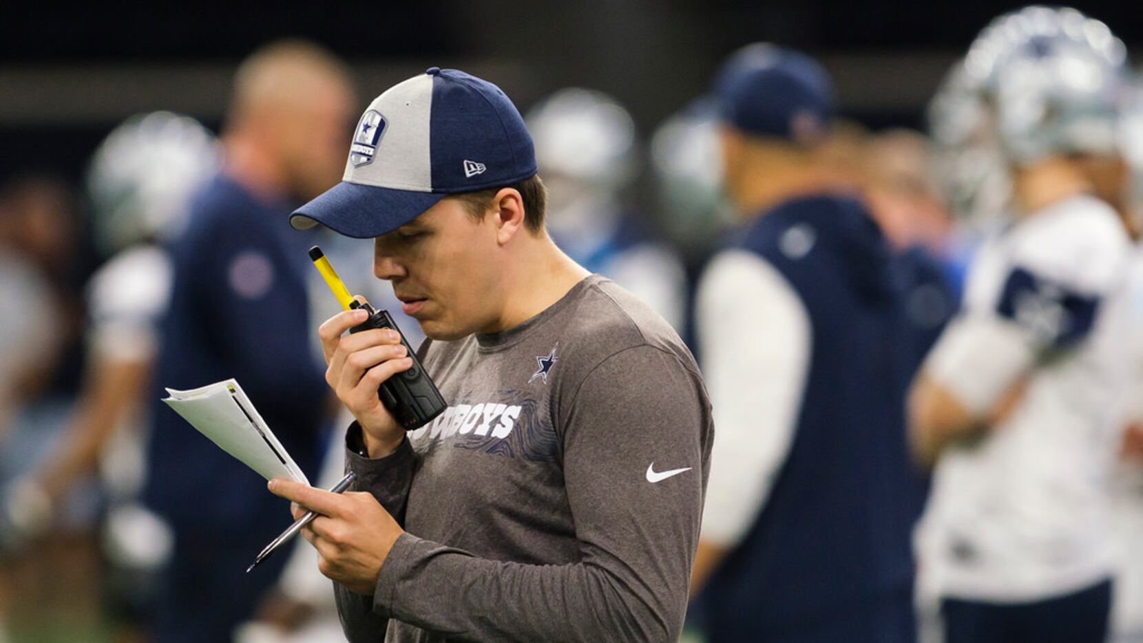 Dallas Cowboys offensive coordinator Kellen Moore talks on a radio during a team OTA...