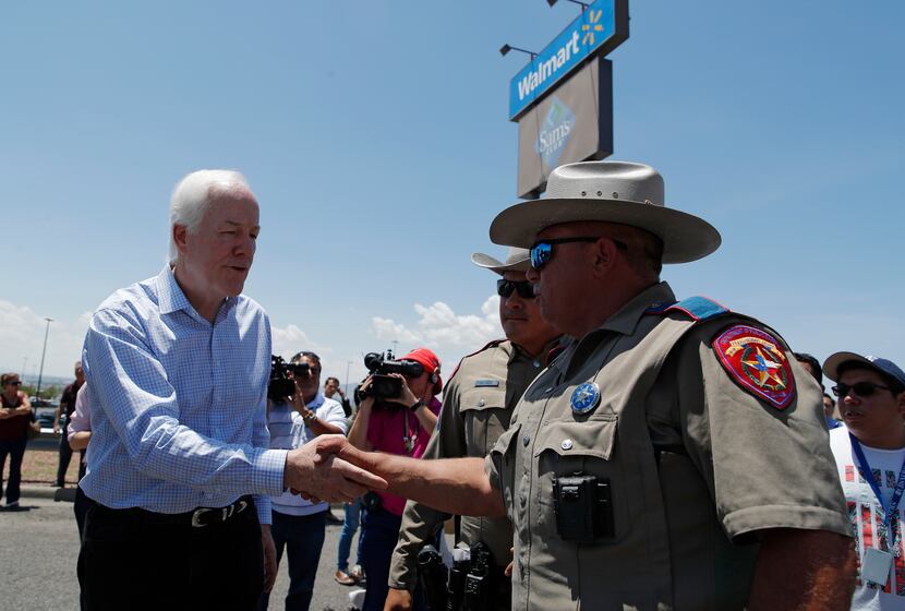 Sen. John Cornyn, R-Texas., left, shakes hands with law enforcement at the scene of a mass...