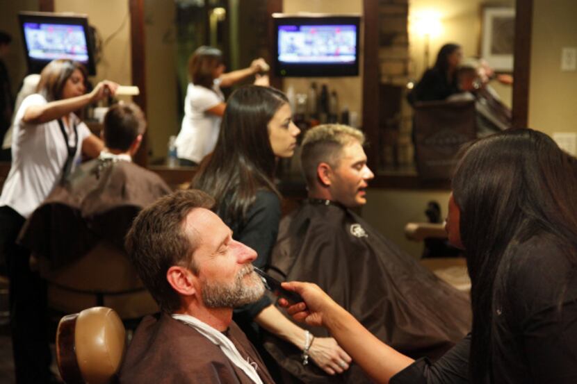 David Baize of Aubrey receives a beard treatment from stylist Nicoya Mothershed at the Gents...