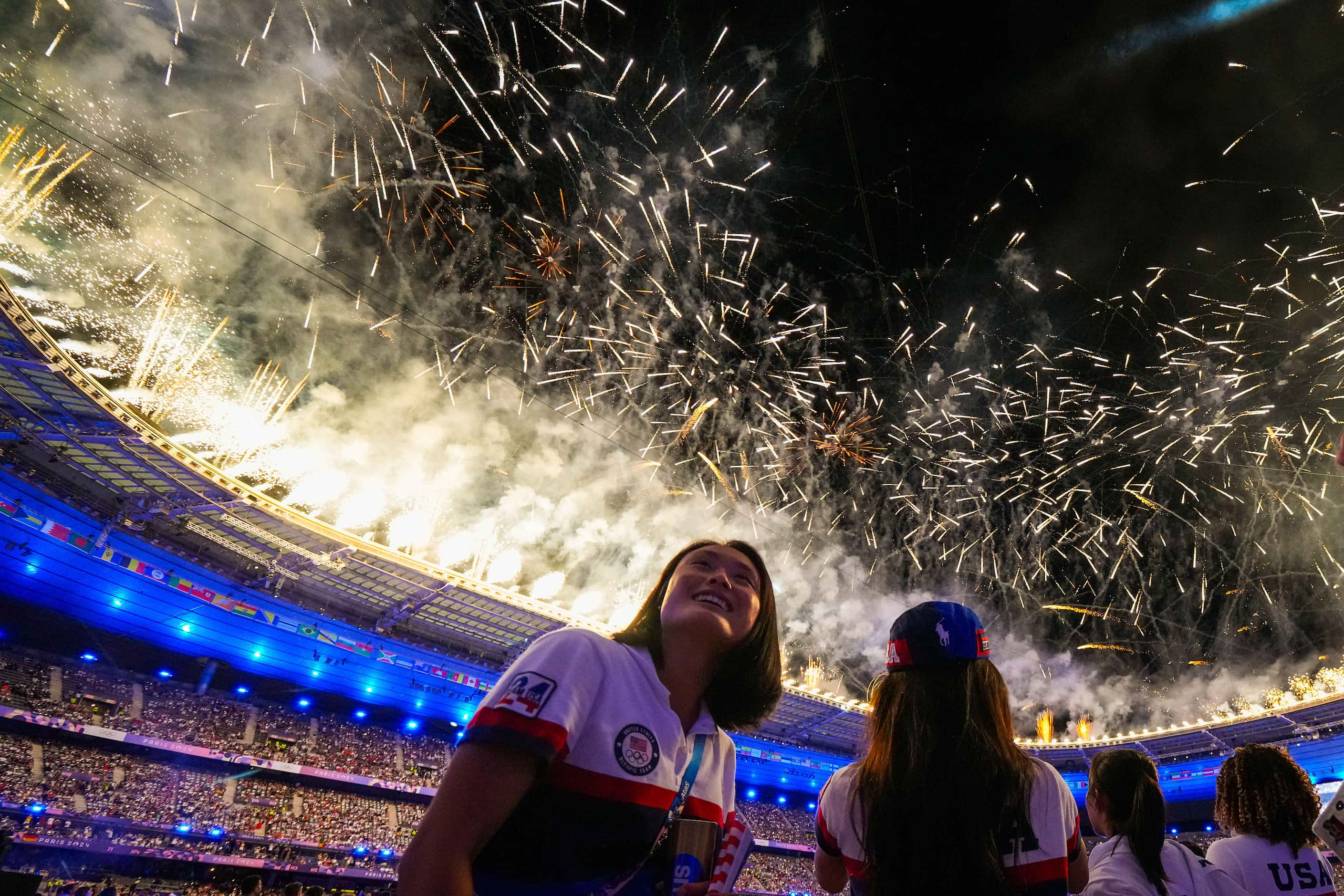 American athletes watch as fireworks expold over the stadium during closing ceremonies for...