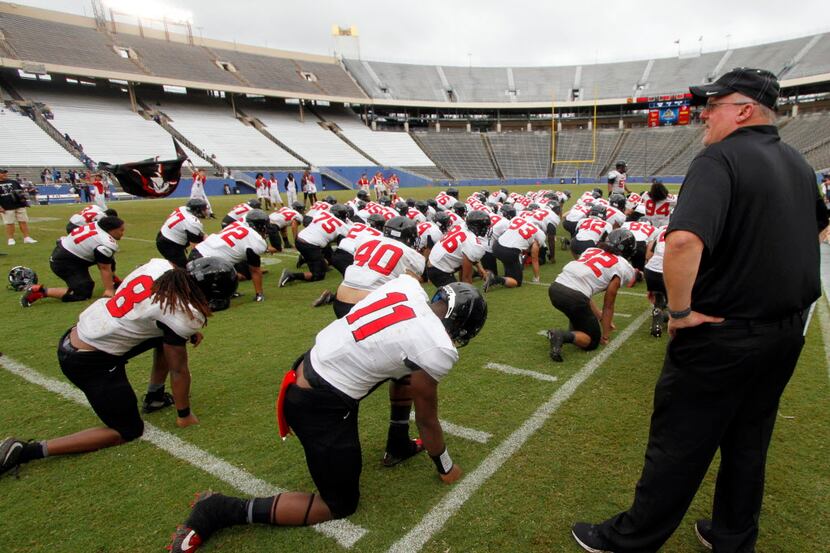 Euless Trinity head coach Chris Jensen watches as his team goes through the movements of a...