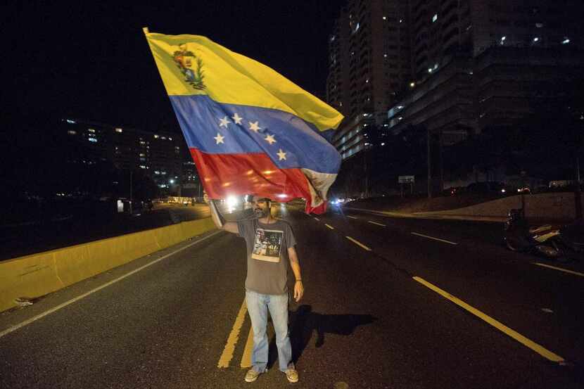 Un dirigente opositor agita una bandera venezolana durante una protesta contra el presidente...