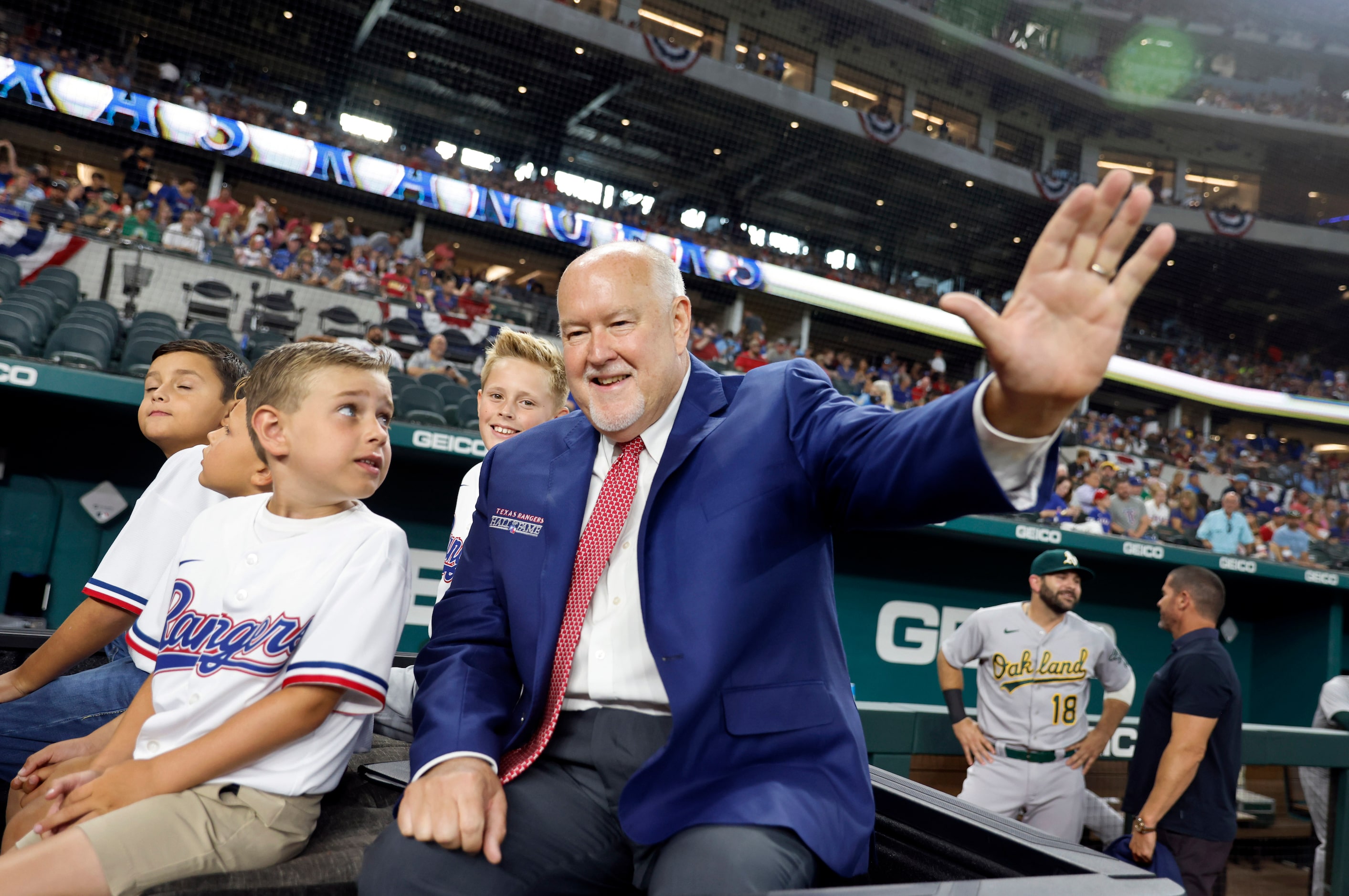 Texas Rangers executive vice president and public address announcer Chuck Morgan waves to...