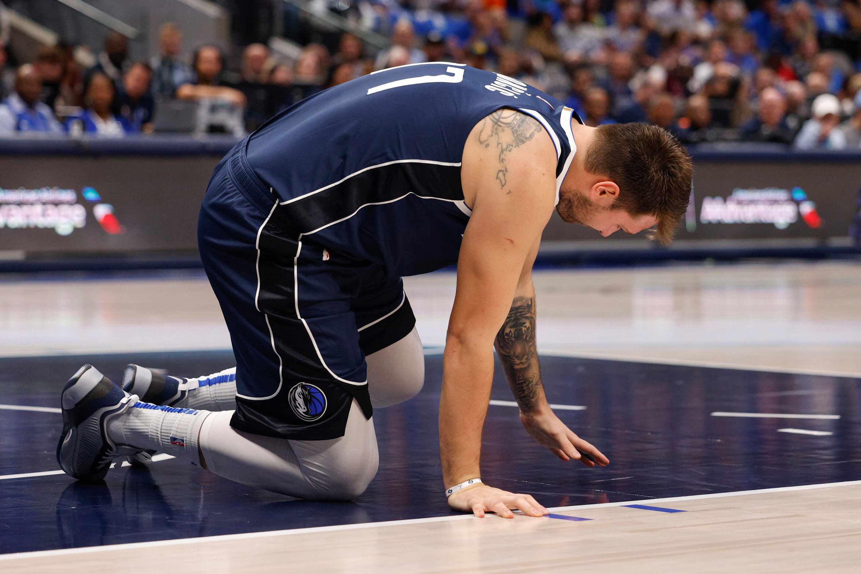 Dallas Mavericks guard Luka Doncic (77) kneels on the ground after appearing to injure his...